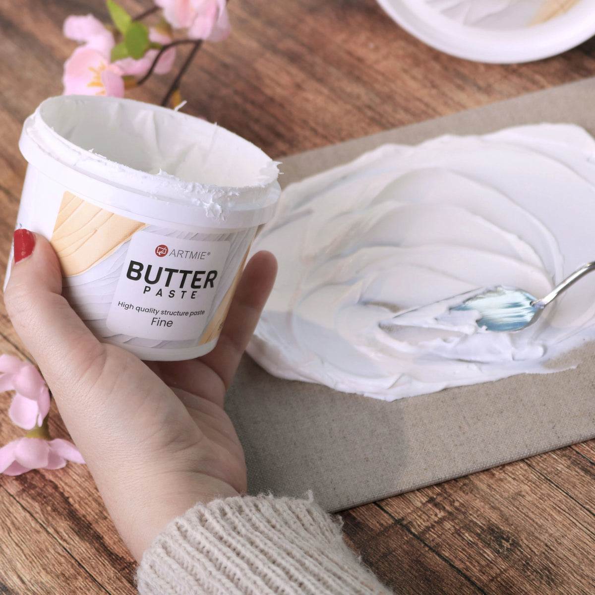 Barattolo aperto e strato di pasta ARTMIE Butter Fine steso su tela con spatola