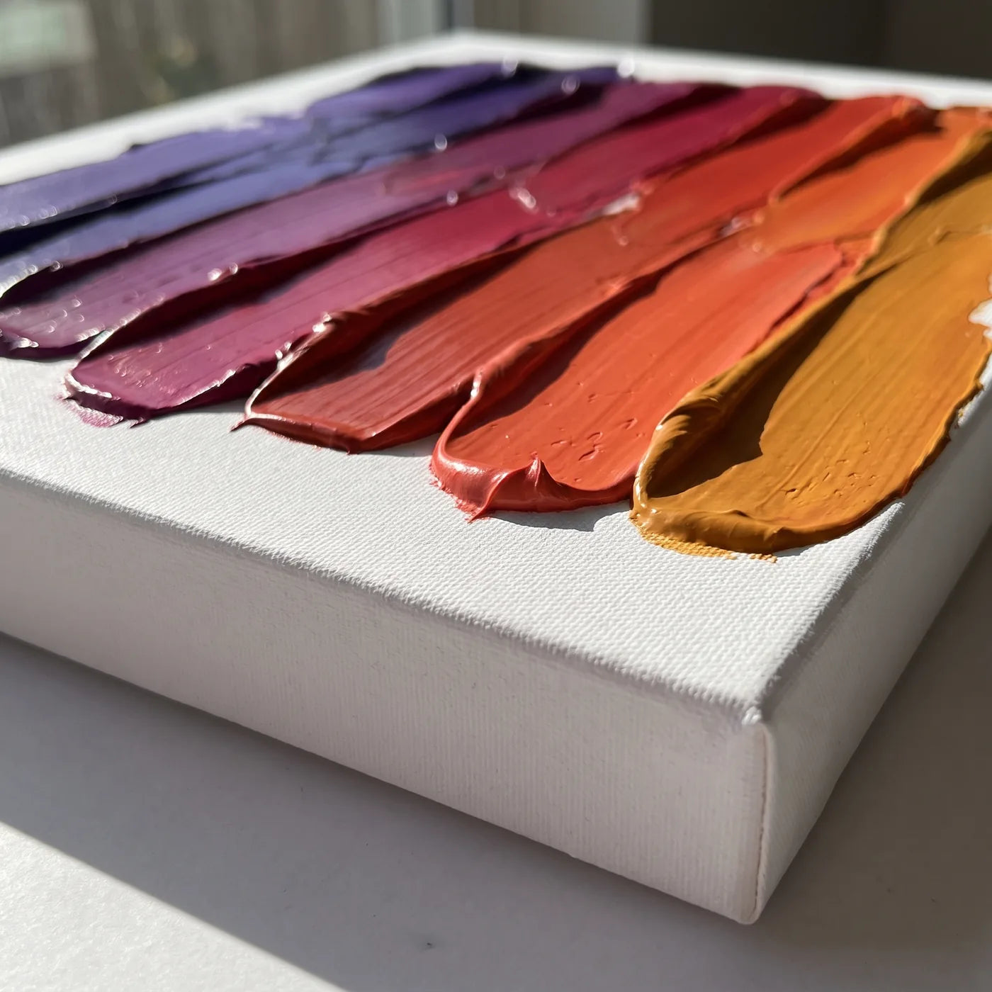 Bordo della tela 3D di lato — lato bianco profondo 4 cm e fasce di colore acrilico denso stese con la spatola, ognuna di un colore diverso, che insieme formano un passaggio dal viola all’ambra